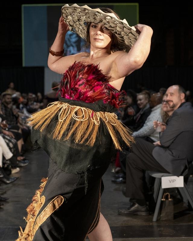 Model in a woven hat and red feathered top at the 2024 show